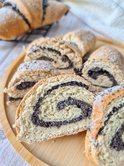 Sliced poppy seed roll on a wooden plate with a white napkin in the background made with ReWild CoreBake
