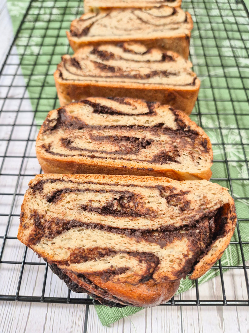 Gluten-free chocolate babka loaf sliced and arranged on a cooling rack made with ReWild CoreBake